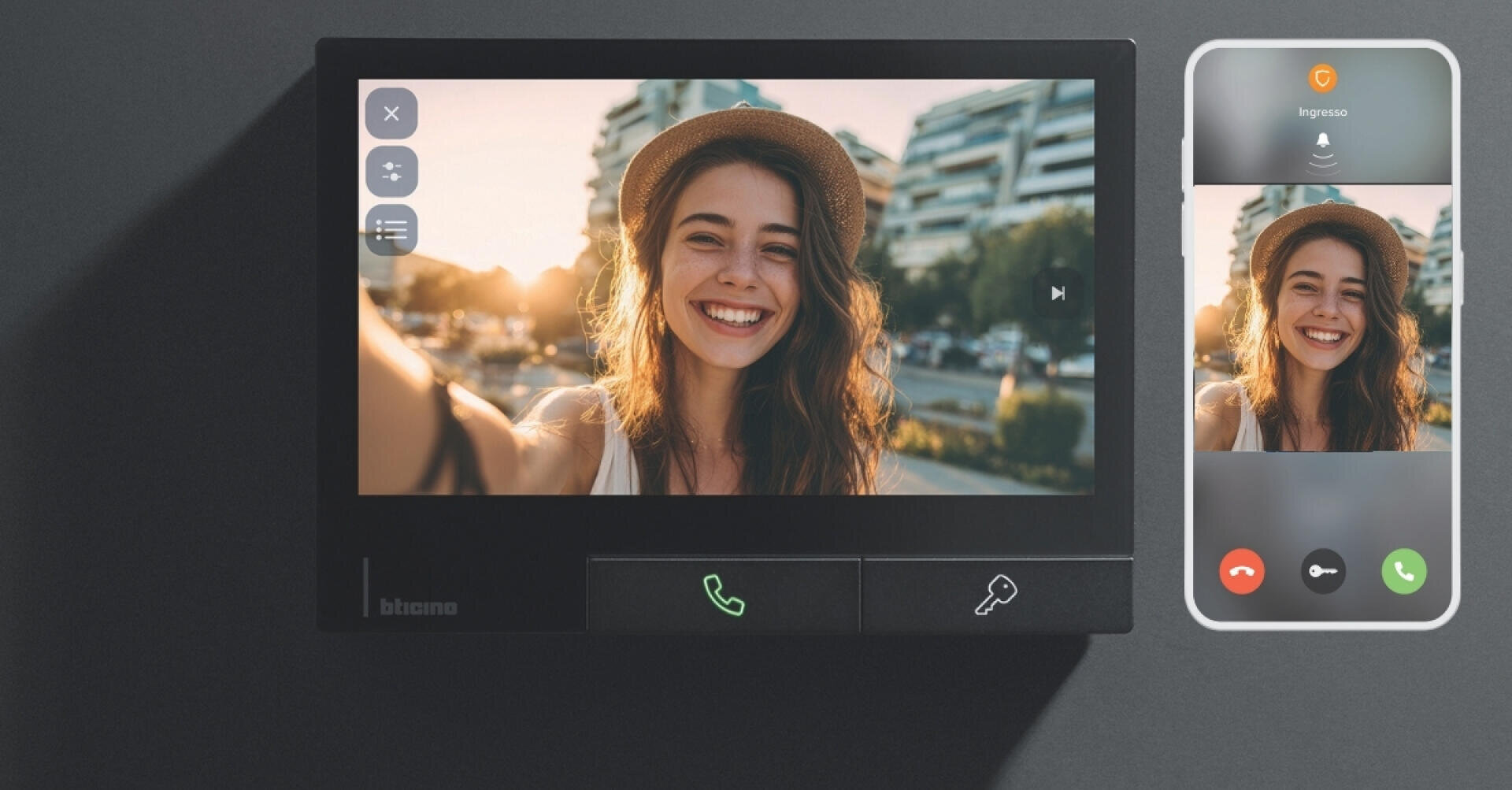 Une jeune femme portant un chapeau sourit tout en prenant un selfie sur un écran affiché à la fois sur un interphone vidéo fixé au mur et sur un smartphone. En arrière-plan, on peut voir des bâtiments urbains et la lumière du soleil.