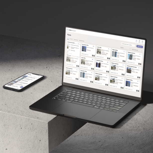 Un smartphone et un ordinateur portable sont posés sur une surface en béton. L'écran de l'ordinateur portable affiche un tableau de bord avec plusieurs fiches de projet, tandis que le smartphone montre une interface similaire, suggérant que les deux accèdent à la même plateforme.